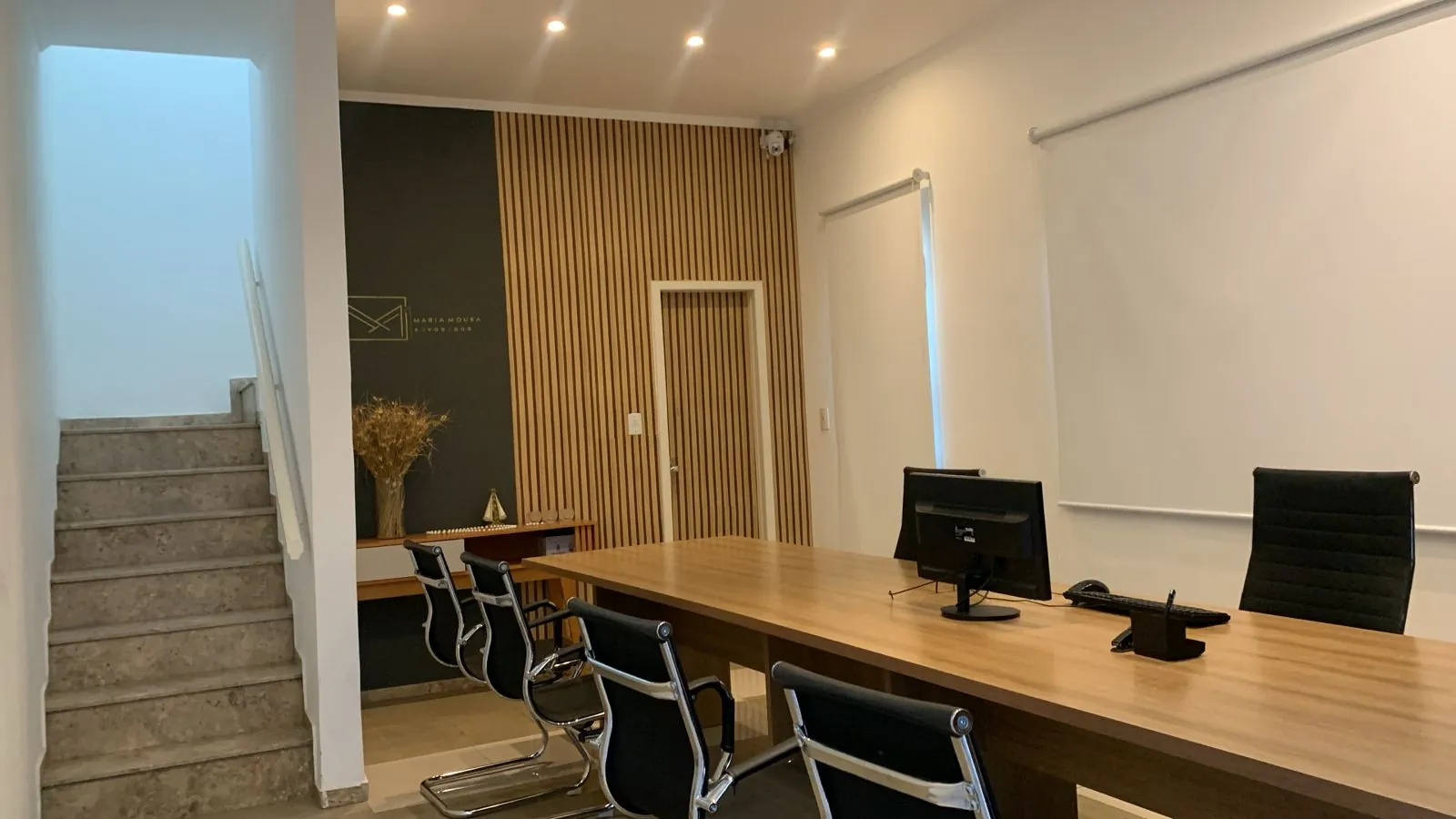 Interior do escritório com parede ripada de madeira e logotipo dourado